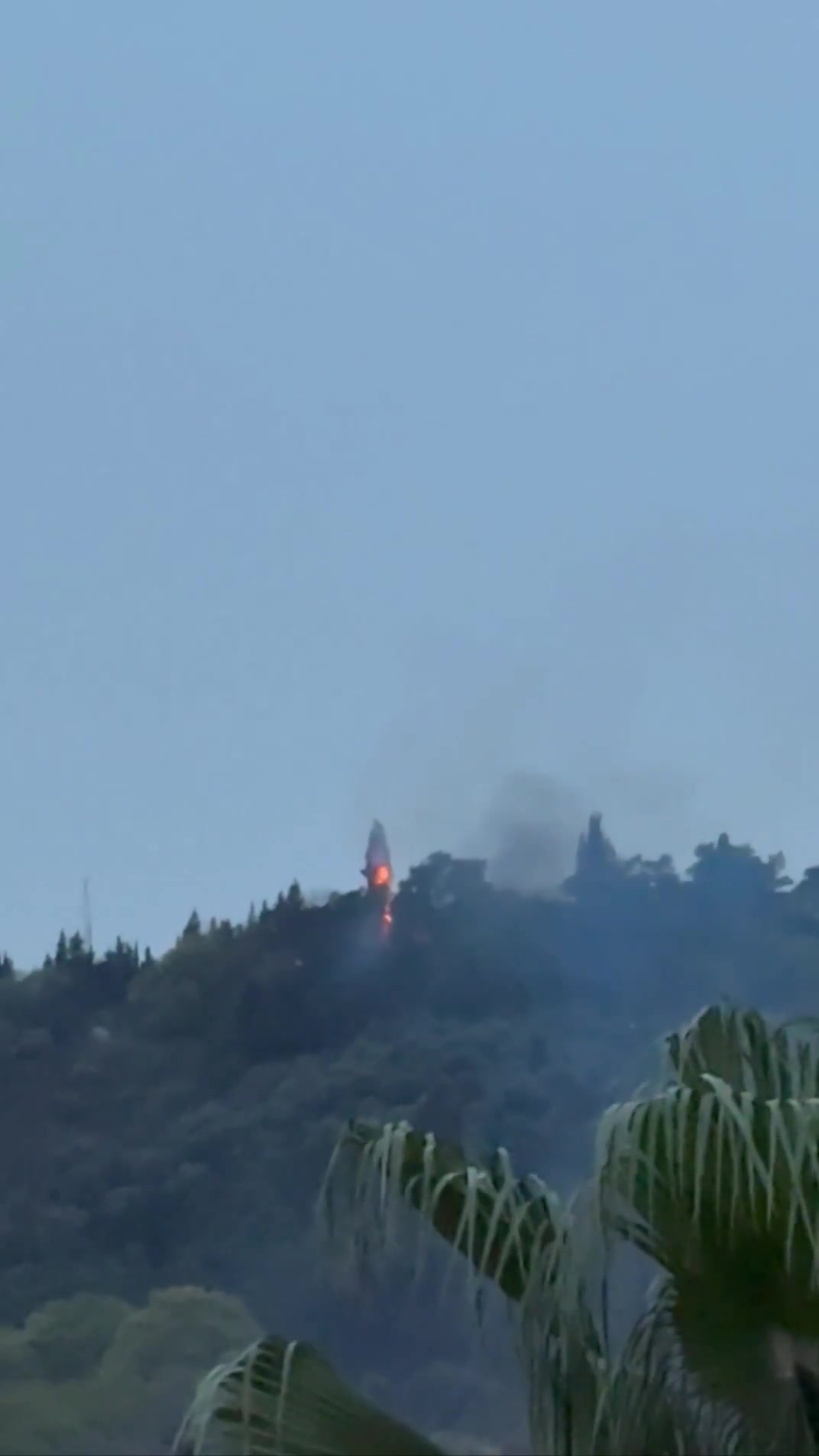 Smoke and fire are seen on top of a hill in the northern city of Behshahr in the early hours of Friday after a strike targeting a radar site
